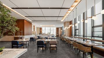 C’est un restaurant moderne doté d’une grande salle à manger, de nombreuses tables et de chaises. De grandes fenêtres laissent entrer la lumière naturelle et offrent une vue sur la ville.