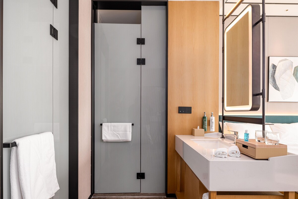 Une salle de bain moderne équipée d’une douche, d’un meuble-lavabo avec miroir et d’un porte-serviettes.