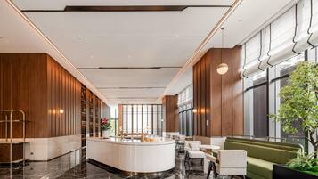 Un hall d’entrée moderne avec un comptoir d’accueil, un espace salon et de grandes fenêtres.