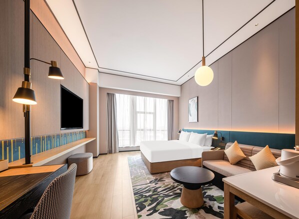 A modern hotel room with a bed, sofa, TV, and a dining area. - Hilton Garden Inn Fenyang Yulongwan (Lvliang)