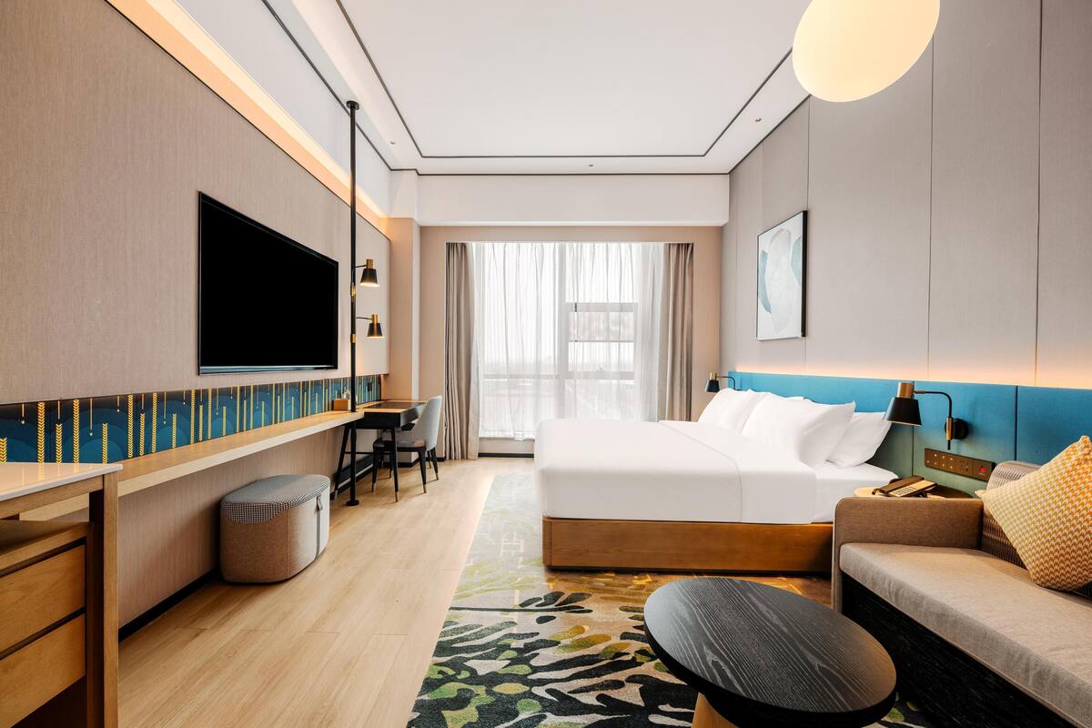 Een moderne hotelkamer met een groot bed, een sofa, een bureau en een televisie.