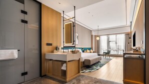 A modern hotel room with a large bed, a vanity with a mirror, a desk, and a large window. - Hilton Garden Inn Fenyang Yulongwan (Lvliang)