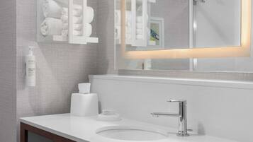 Une salle de bain moderne avec un lavabo blanc, un robinet chromé et un miroir doté d’un cadre lumineux.