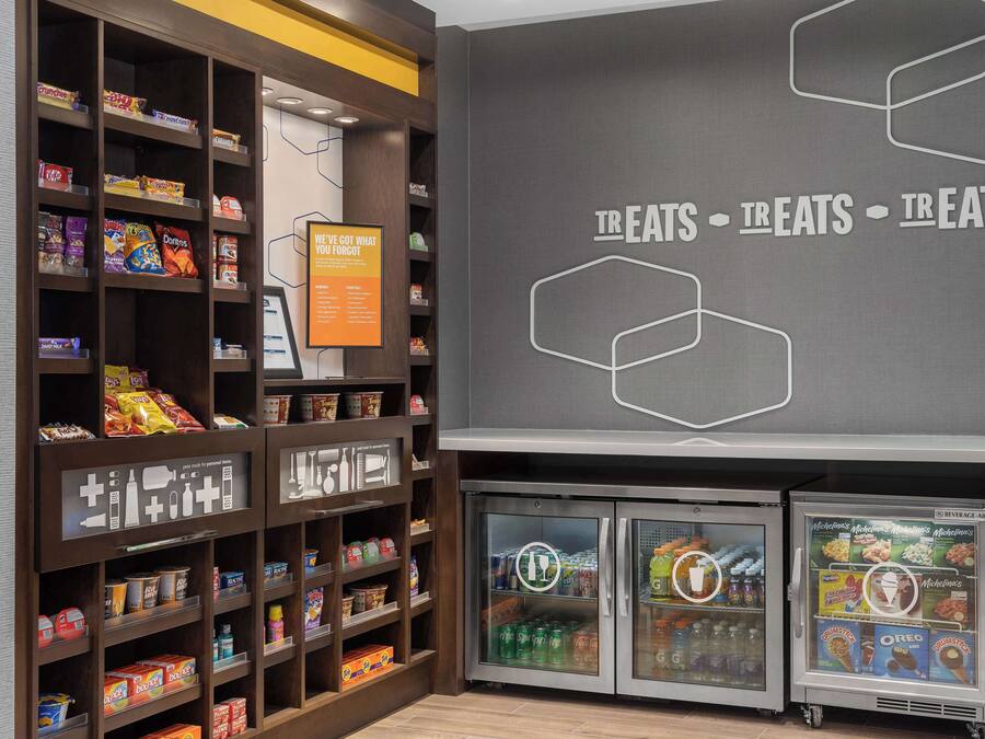 A snack display with various packaged snacks and a beverage cooler.