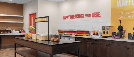 Ein Frühstücksbereich mit einem Schild, auf dem steht: 'HAPPY BREAKFAST STARTS HERE'.