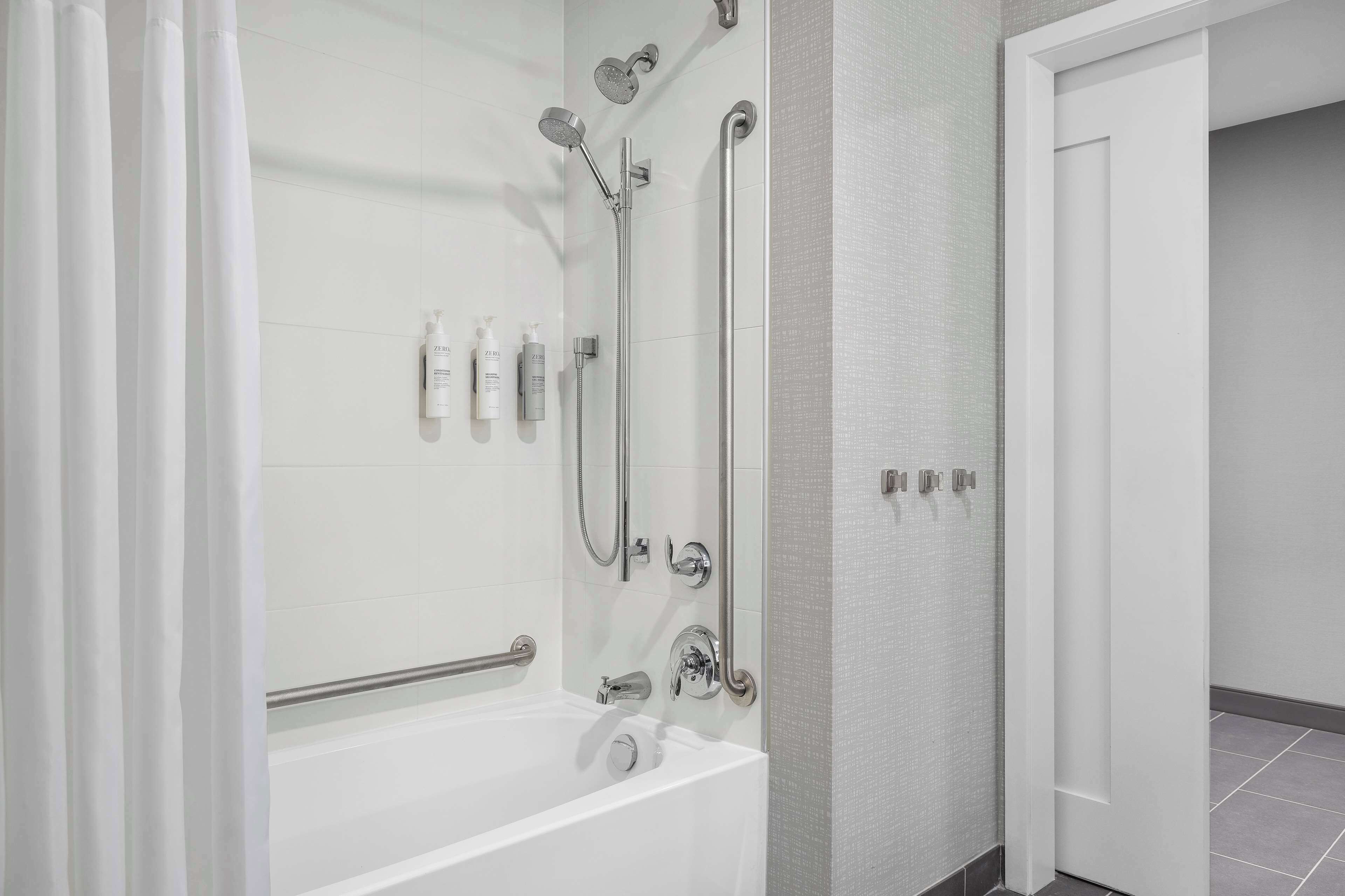 A modern bathroom with a walk-in shower, grab bars, and a bathtub.