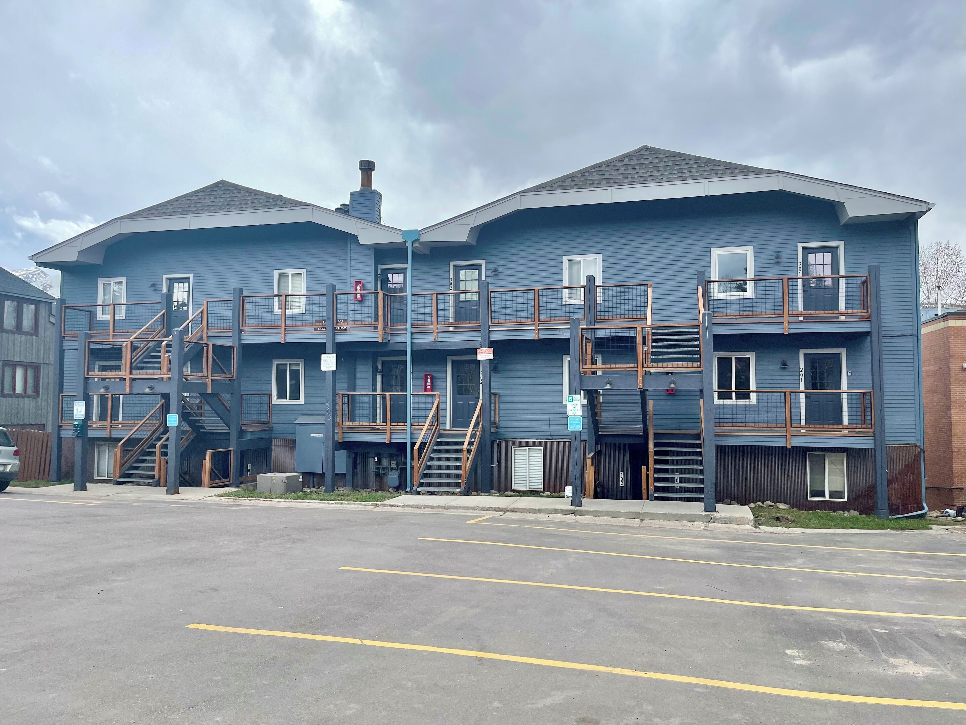 A multi-story building with external staircases, balconies, and a parking lot in front.