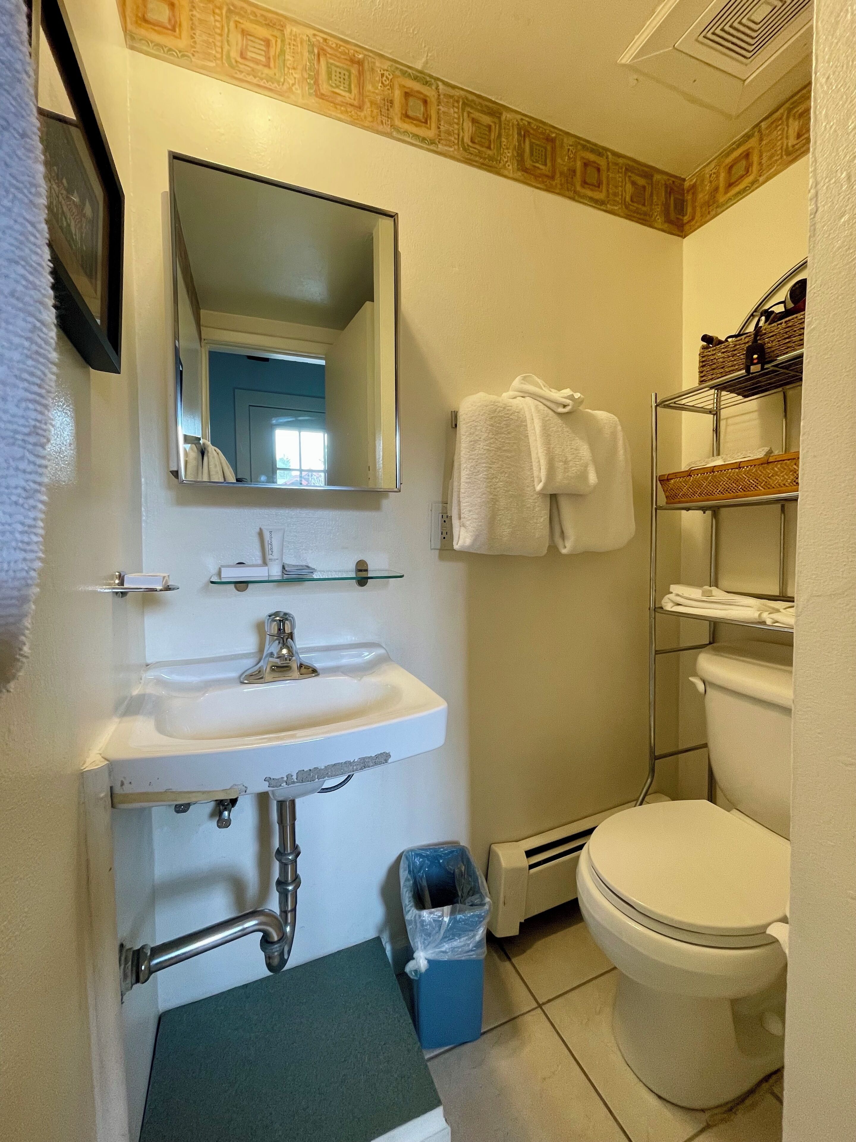 Une salle de bain équipée d’un lavabo, d’un miroir, d’un porte-serviettes et de toilettes.