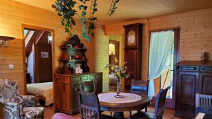 A cozy room with a wooden interior, a round table with chairs, a piano, a clock, and a radiator. - Chalet in the mountains, Massif du Vercors, 1100 meters, Piano at your disposal (Lans-en-Vercors)