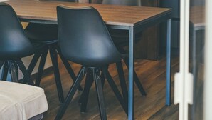 A modern dining area with a wooden table and black chairs. - Superb 1-Bedroom Penthouse with a View of the Dolomites (Large) (Trentino-Alto Adige)