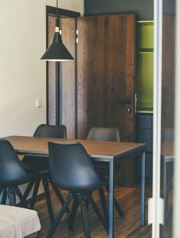 A modern dining area with a wooden table and black chairs. - Superb 1-Bedroom Penthouse with a View of the Dolomites (Large) (Trentino-Alto Adige)