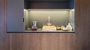 A compact kitchenette with a coffee machine, a sink, and a small countertop. - Superb 1-Bedroom Penthouse with a View of the Dolomites (Large) (Trentino-Alto Adige)