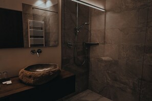 A modern bathroom with a stone sink, a handheld showerhead, and a towel rack. - Superb 1-Bedroom Penthouse with a View of the Dolomites (Large) (Trentino-Alto Adige)
