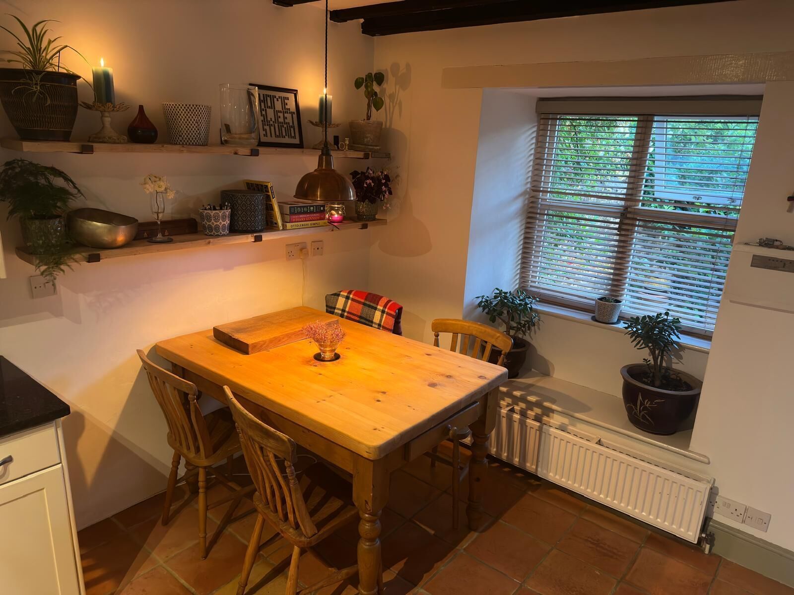 A cozy kitchen with a wooden table, chairs, and a window with blinds.
