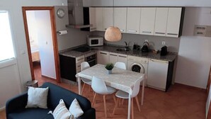 A compact kitchen with white cabinets, a microwave, a sink, and a dining area with a table and chairs. - Charming house just two minutes from the historic center of Ayamonte. (Ayamonte)
