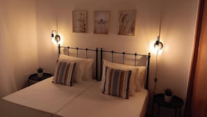 A double bed with a metal frame, two bedside tables with lamps, and three wall-mounted artworks. - Charming house just two minutes from the historic center of Ayamonte. (Ayamonte)