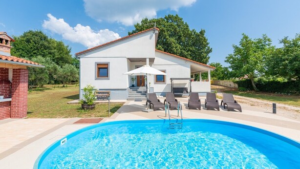 A modern house with a swimming pool, outdoor seating, and a barbecue area.