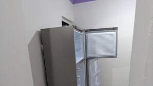 Una habitación de esquina con refrigerador incorporado y un mueble pequeño.