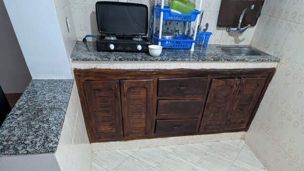 Una cocina con encimera de granito, estufa, fregadero y un mueble azul.