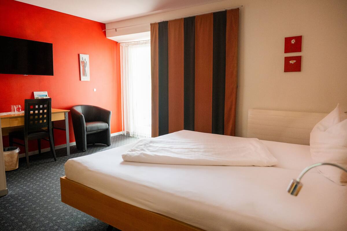 Ein Hotelzimmer mit Bett, Schreibtisch, Stuhl und Fernseher.