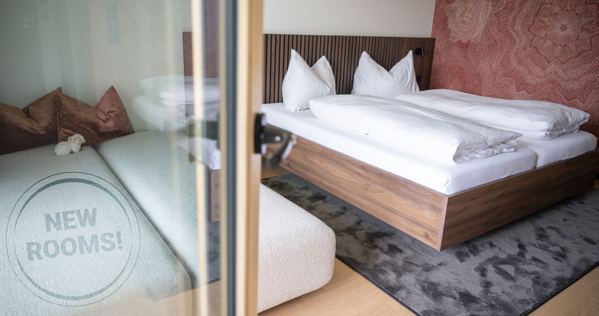 Una habitación de hotel moderna con una cama de madera, ropa de cama blanca y alfombra gris.