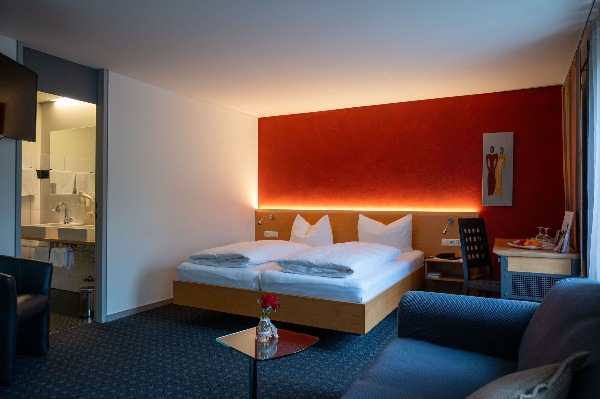 Ein Hotelzimmer mit Bett, Nachttisch und einem kleinen Tisch mit Blumenvase.