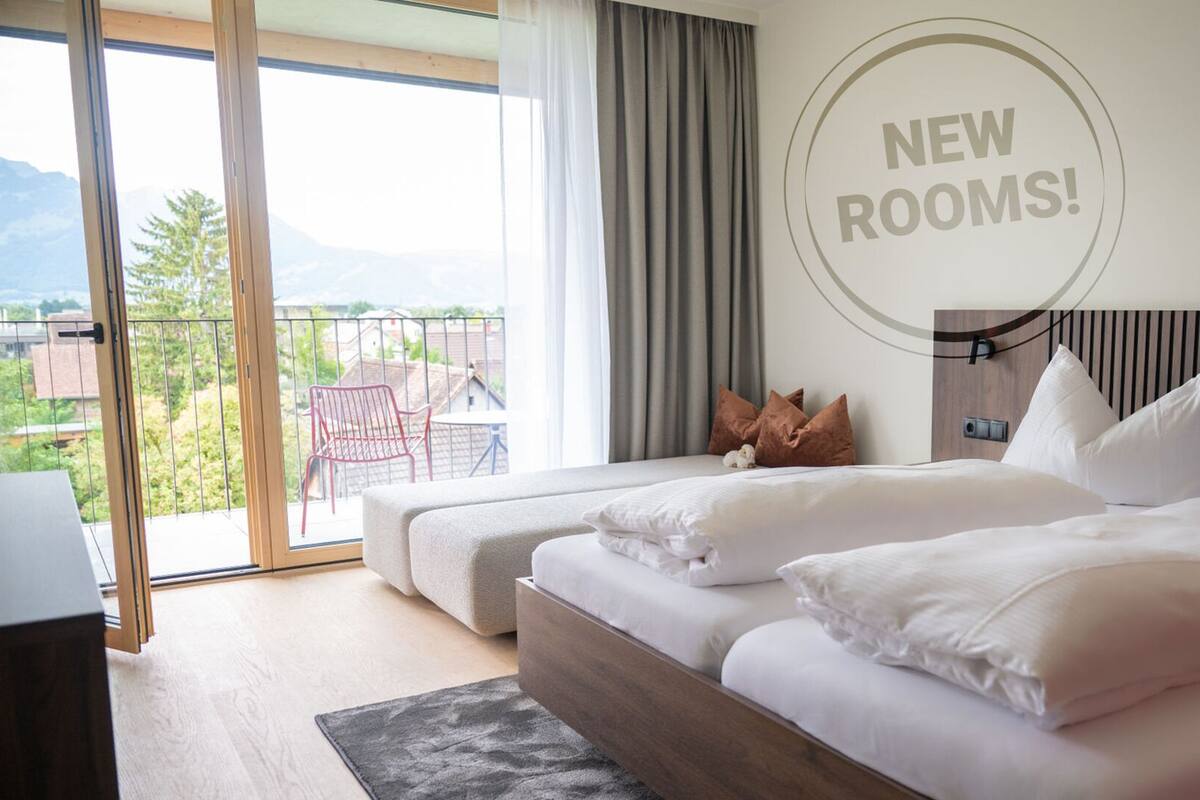 Ein Hotelzimmer mit zwei Betten und Blick ins Freie, mit einem Schild, das auf neue Zimmer hinweist.
