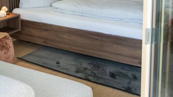 Ein modernes Schlafzimmer mit einem Holzkopfende, einem Bett mit weißer Bettwäsche und einem Nachttisch mit Lampe.