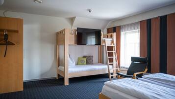 A bunk bed room with a TV mounted above it, a chair, and a desk with a telephone.