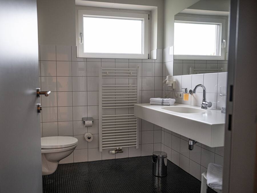 A bathroom with a toilet, sink, towel rack, and a window.