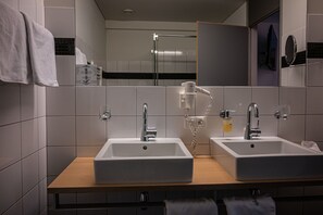 Un baño moderno con dos lavamanos, un secador de pelo y un espejo.
