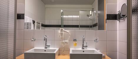 Un baño con dos lavamanos, un espejo y un perchero para toallas.
