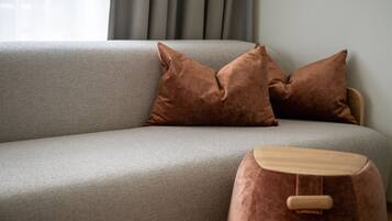 A grey sofa with two brown cushions and a wooden ottoman.
