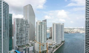 Un complejo de edificios de gran altura con varias torres residenciales, vista al agua y grúas de construcción que señalan desarrollo en curso.