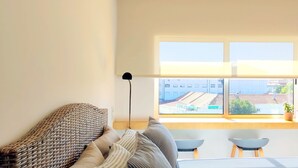 A room with a large window, a sofa, a floor lamp, and two small tables. - ihW 1-bedroom Apartment Sunny & Comfy (Espinho)