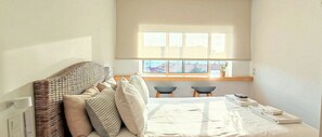 Un dormitorio con cama, dos sillas, ventana con vistas y una mesita con toallas.