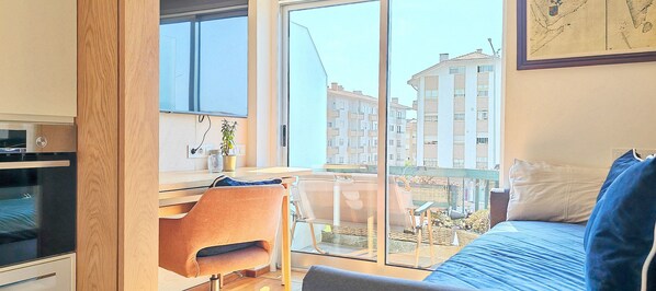 Una habitación con una ventana grande, un escritorio, una silla y una cama.