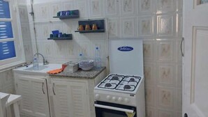 A compact kitchen with white cabinetry, a gas stove, a refrigerator, and a sink.