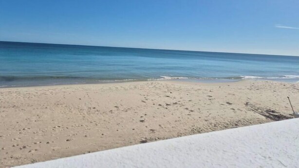 A beach with a clear sky and calm sea.