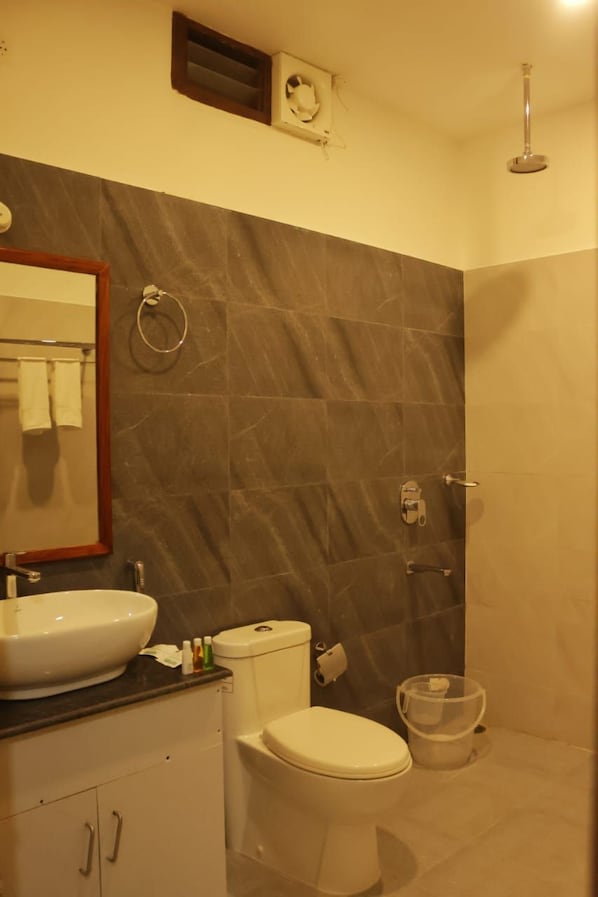 Un baño con lavamanos, inodoro y ducha blancos.