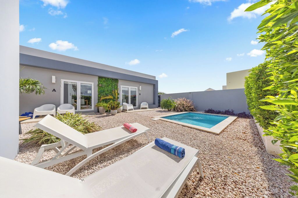 A modern outdoor pool area with lounge chairs, a small pool, and a gravel surface.