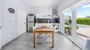 A modern kitchen with a dining area, a built-in oven, and a view of a swimming pool. - 5 min Eagle Beach | New Luxury 1BR w/ Pool & BBQ (Noord)