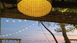 Un espace aménagé près de la plage, avec des tables et des chaises, une balançoire et une vue sur l’océan.
