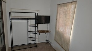 A small, sparsely furnished room with a bunk bed, a flat-screen TV, and a window with blinds. - Cuba Mía  (Burriana)