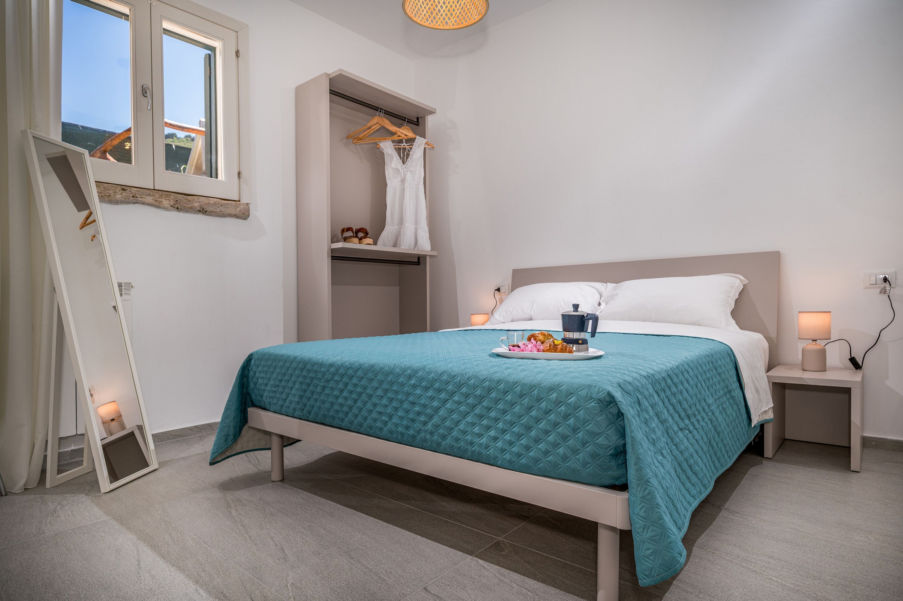 Un dormitorio con cama, mesitas de noche, armario y ventana.