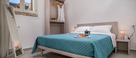 Un dormitorio con cama, mesitas de noche, armario y ventana.