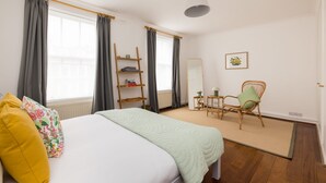 Ein Schlafzimmer mit einem Bett, einem Sessel, einem Regal und einem Spiegel.