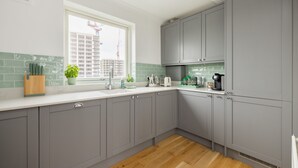 Eine moderne Küche mit grauen Schränken, einer weißen Arbeitsplatte und einem Holzboden.