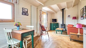 Una habitación acogedora con una mesa de madera, sillas, un sofá y una televisión.