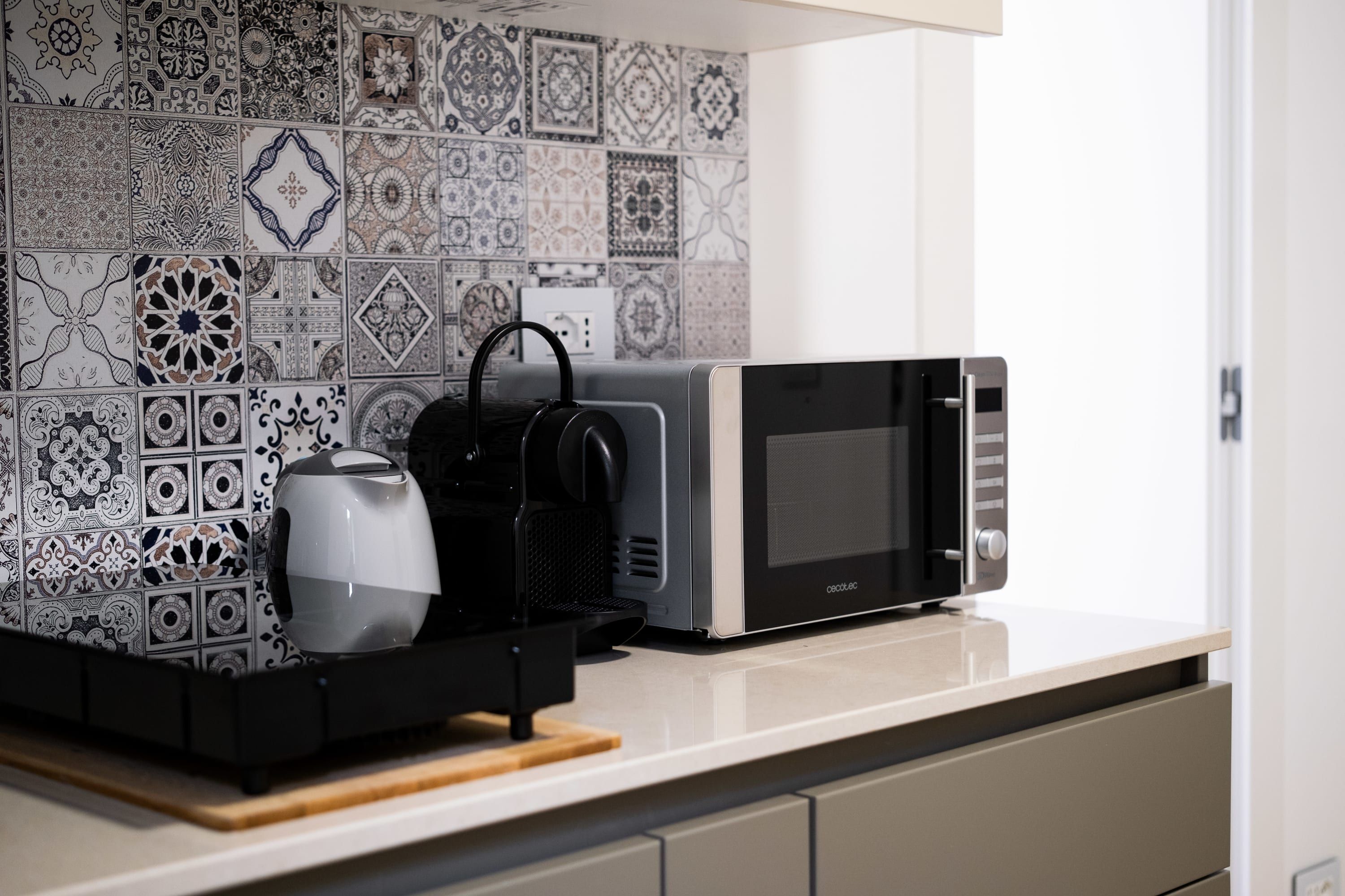 Une cuisine équipée d’un four à micro-ondes, d’une bouilloire et d’une machine à café, le tout posé sur un plan de travail.
